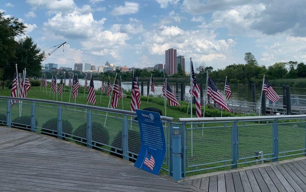 he city of Wilmington rises in the background as Rotary Club flags wave along the Riverwalk.