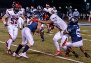 Josiah Torres left and Ian Nance right bring down Chris Trumbull of Red Lion. Photo by DarJuan Pitts