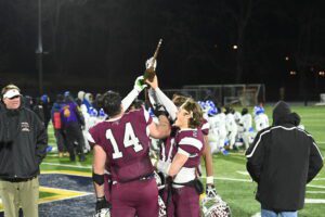 Caravel Academy football lifts the state championship trophy after defeating Howard . Photo by Nick Halliday