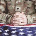 american soldier mourning praying with american flag front him scaled e1747848375578